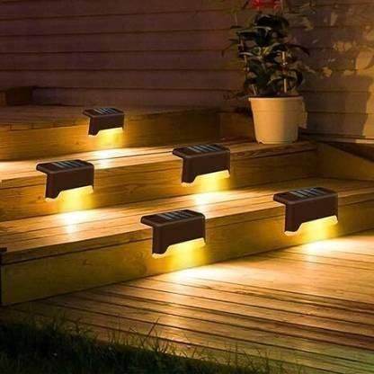Outdoor solar stair lights glowing warm yellow installed on wooden steps at night