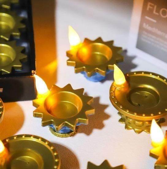 Golden LED water pouring diya light with glowing flame shaped LED bulbs on a white surface